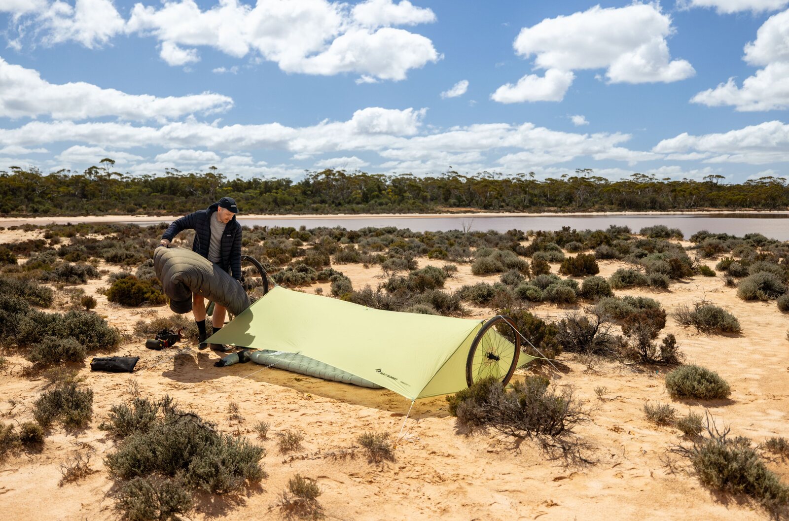 Bikepacking bivy setup beside a salt lake, tarp shelter and bike wheel visible